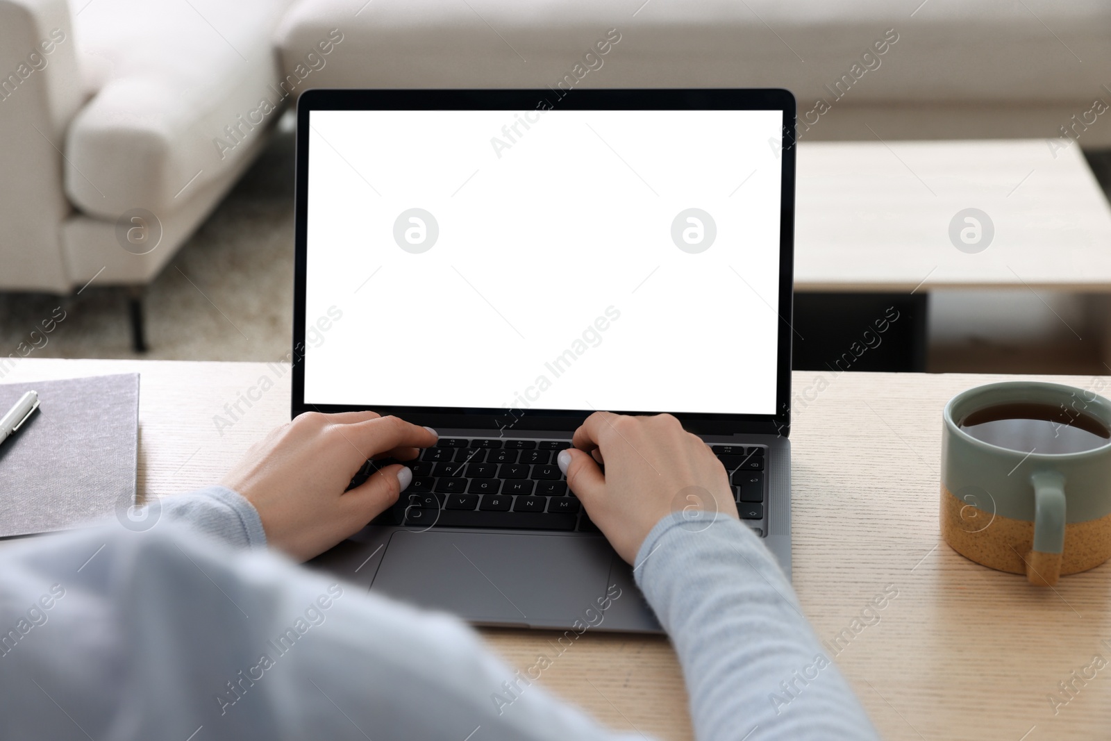 Photo of Woman working with laptop at wooden desk indoors, closeup
