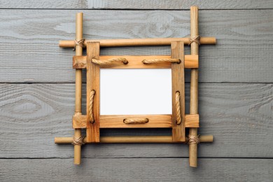 Photo of Empty bamboo frame on grey wooden background, top view. Space for text