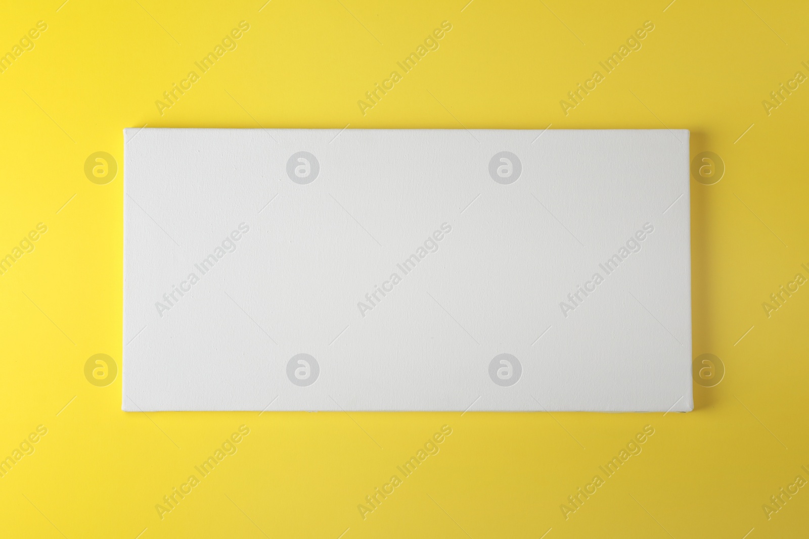 Photo of Blank canvas on yellow background, space for text