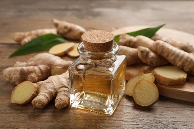Photo of Glass bottle of essential oil and ginger root on wooden table