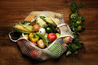 Photo of Different fresh vegetables and fruits in net bag on wooden table, top view. Farmer harvesting