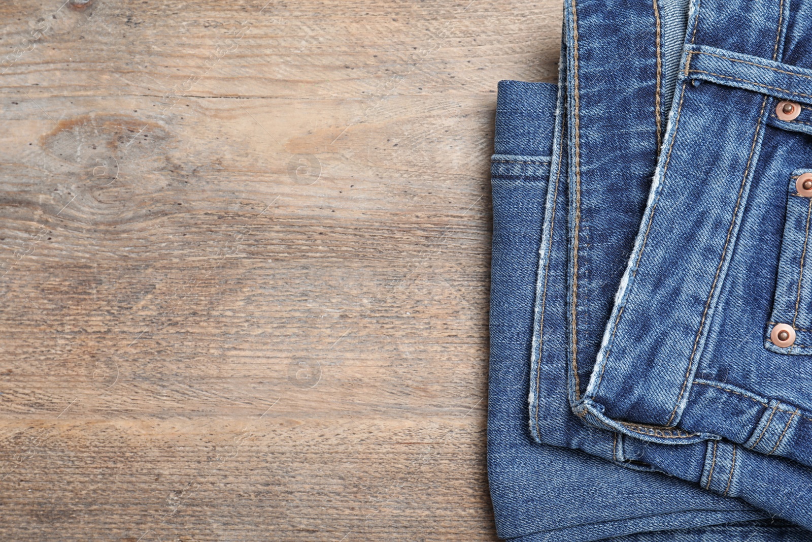 Photo of Stylish jeans on wooden background, top view. Space for text