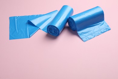 Photo of Rolls of light blue garbage bags on pink background. Space for text