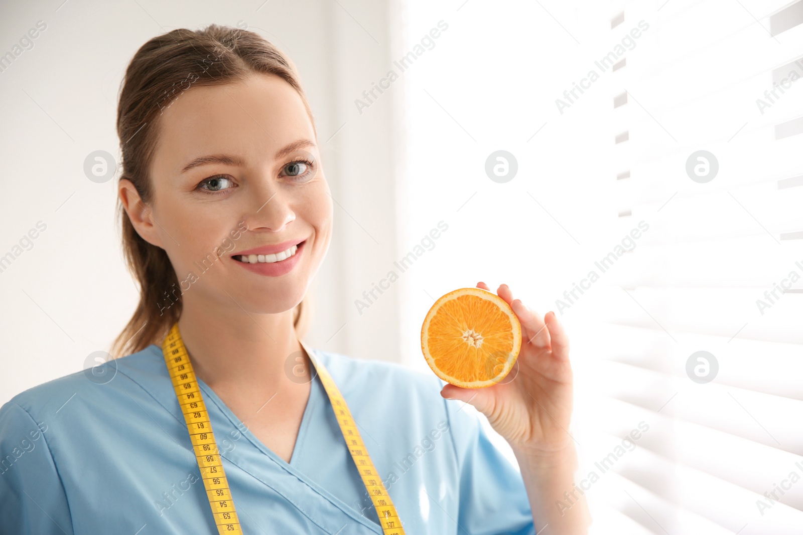 Photo of Nutritionist with orange near window in office