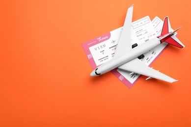 Photo of Toy airplane and tickets on orange background, flat lay with space for text. Travel agency concept