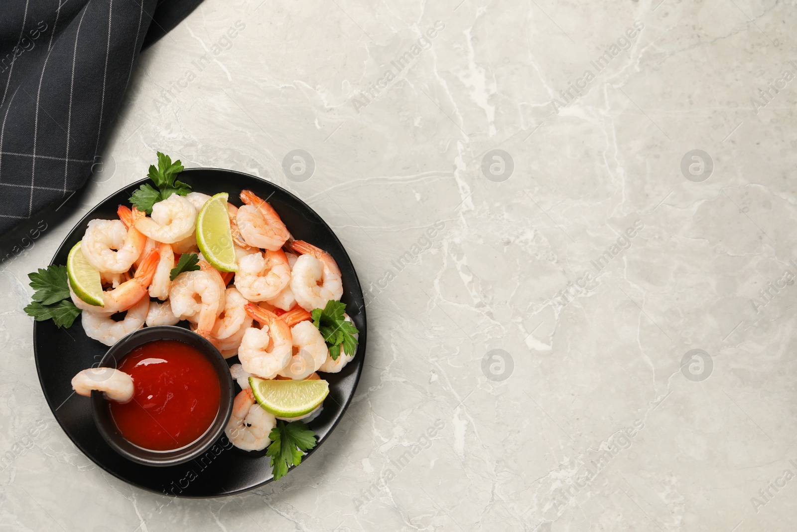 Photo of Tasty boiled shrimps with cocktail sauce, parsley and lime on light grey table, top view. Space for text