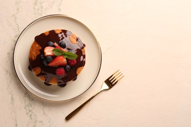 Stack of tasty pancakes with fresh berries and chocolate sauce on white table, top view. Space for text