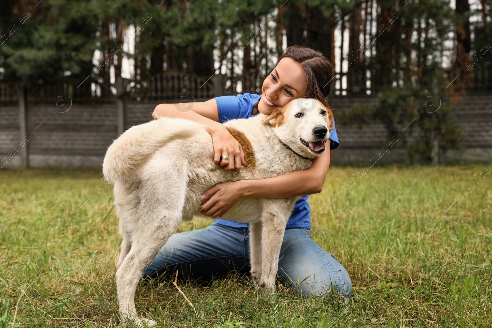 Photo of Female volunteer with homeless dog at animal shelter outdoors