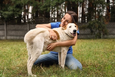 Female volunteer with homeless dog at animal shelter outdoors