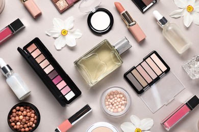 Photo of Flat lay composition with different makeup products and beautiful spring flowers on grey background