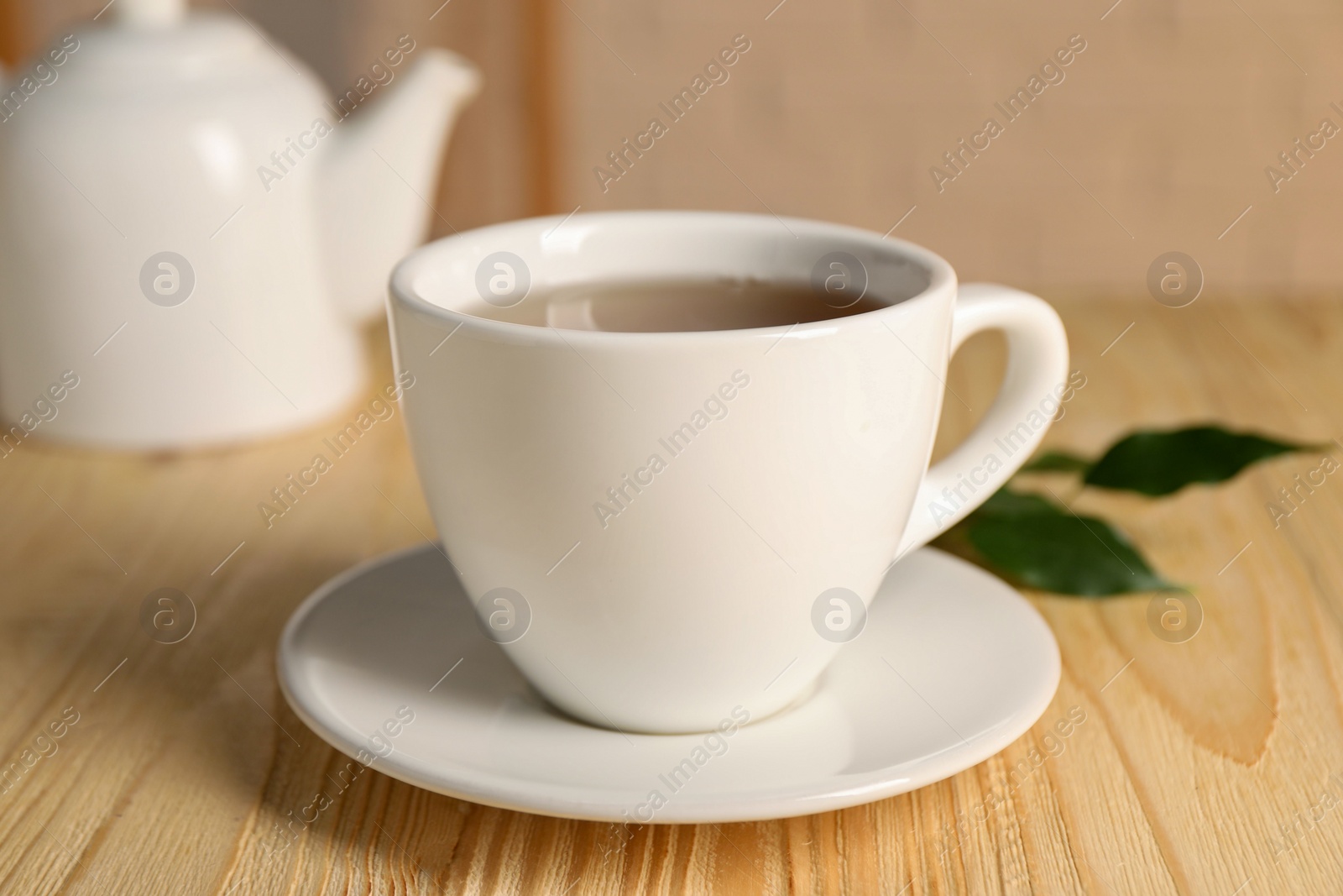 Photo of Tasty tea in cup on light wooden table, closeup