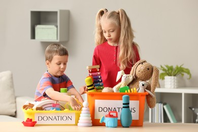 Photo of Cute little children sorting donation boxes at home