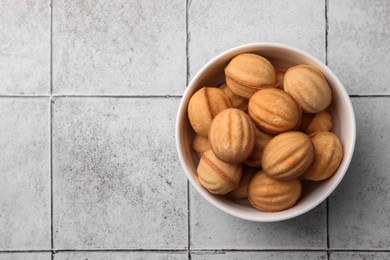 Photo of Delicious nut shaped cookies with boiled condensed milk in bowl on light textured table, flat lay. Space for text