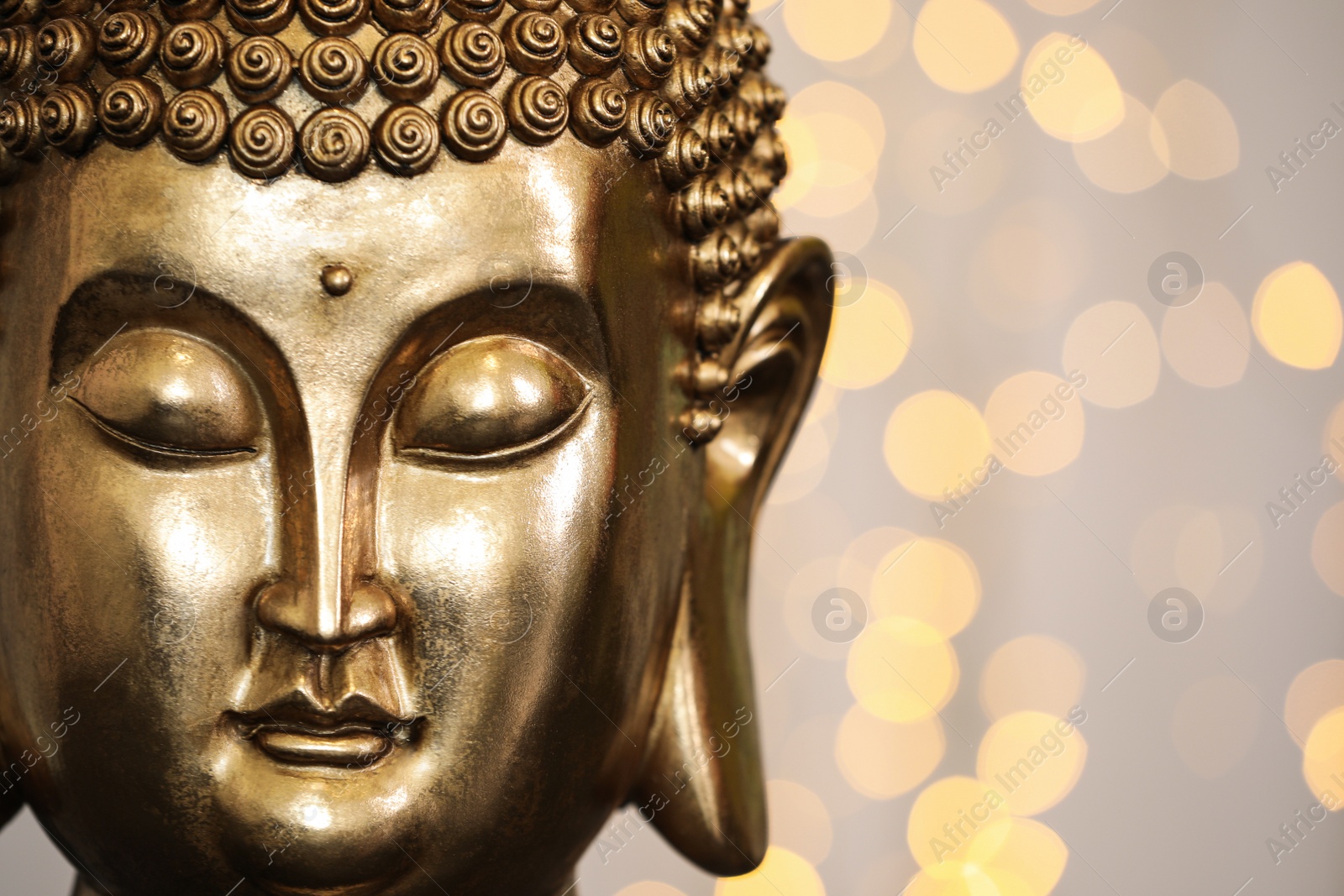 Photo of Buddha statue against blurred lights, closeup. Space for text