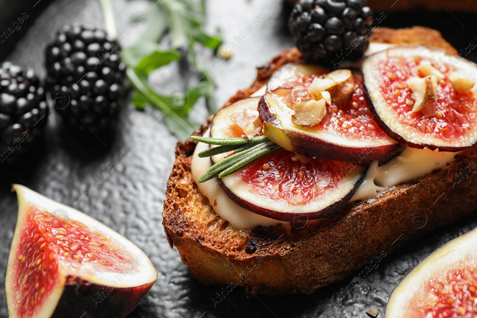 Photo of Bruschettas with cream cheese, figs and blackberries on slate plate, closeup