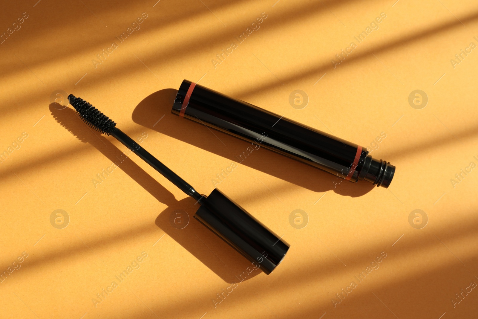 Photo of Mascara for eyelashes on orange background, flat lay. Makeup product