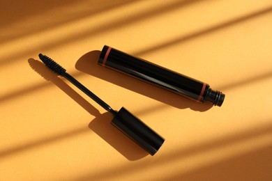 Mascara for eyelashes on orange background, flat lay. Makeup product