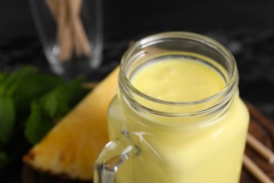 Photo of Tasty pineapple smoothie in mason jar, closeup. Space for text