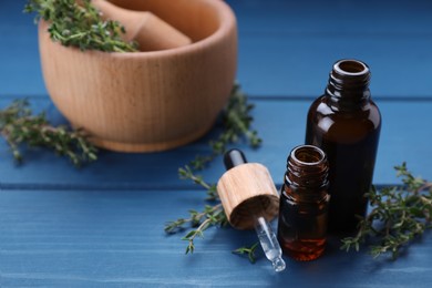Photo of Thyme essential oil on light blue wooden table