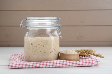 Photo of Leaven and ears of wheat on white wooden table