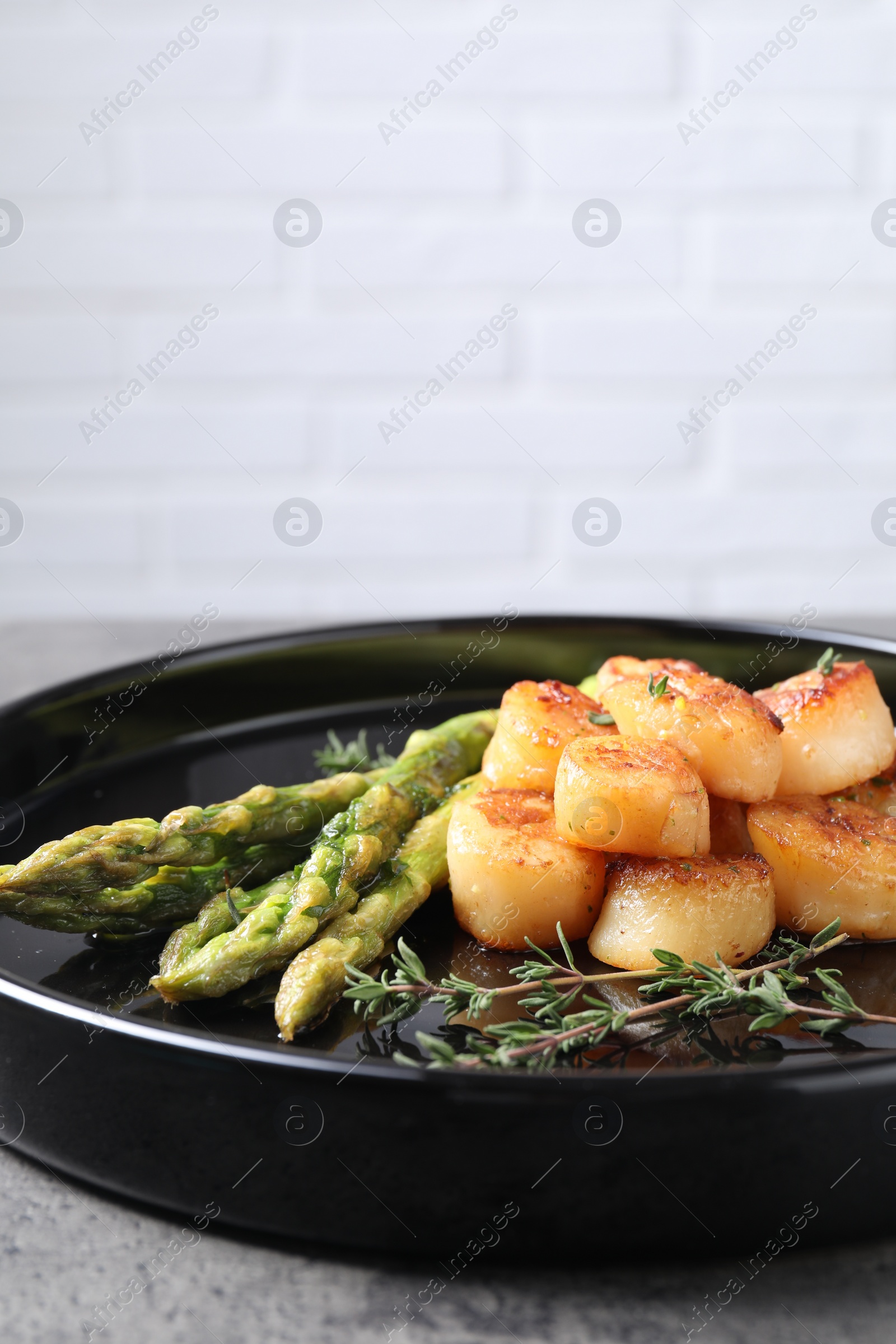 Photo of Delicious fried scallops with asparagus and thyme on plate, space for text