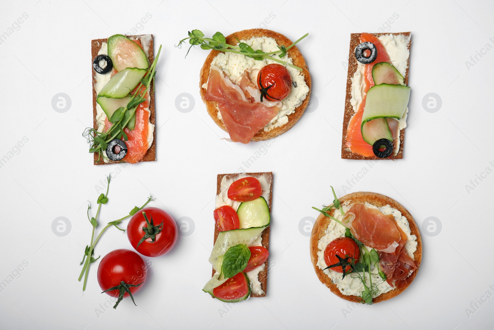 Photo of Tasty rusks and rye crispbreads with different toppings on white background, top view