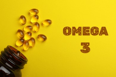 Omega 3. Bottle and fish oil capsules on yellow background, top view