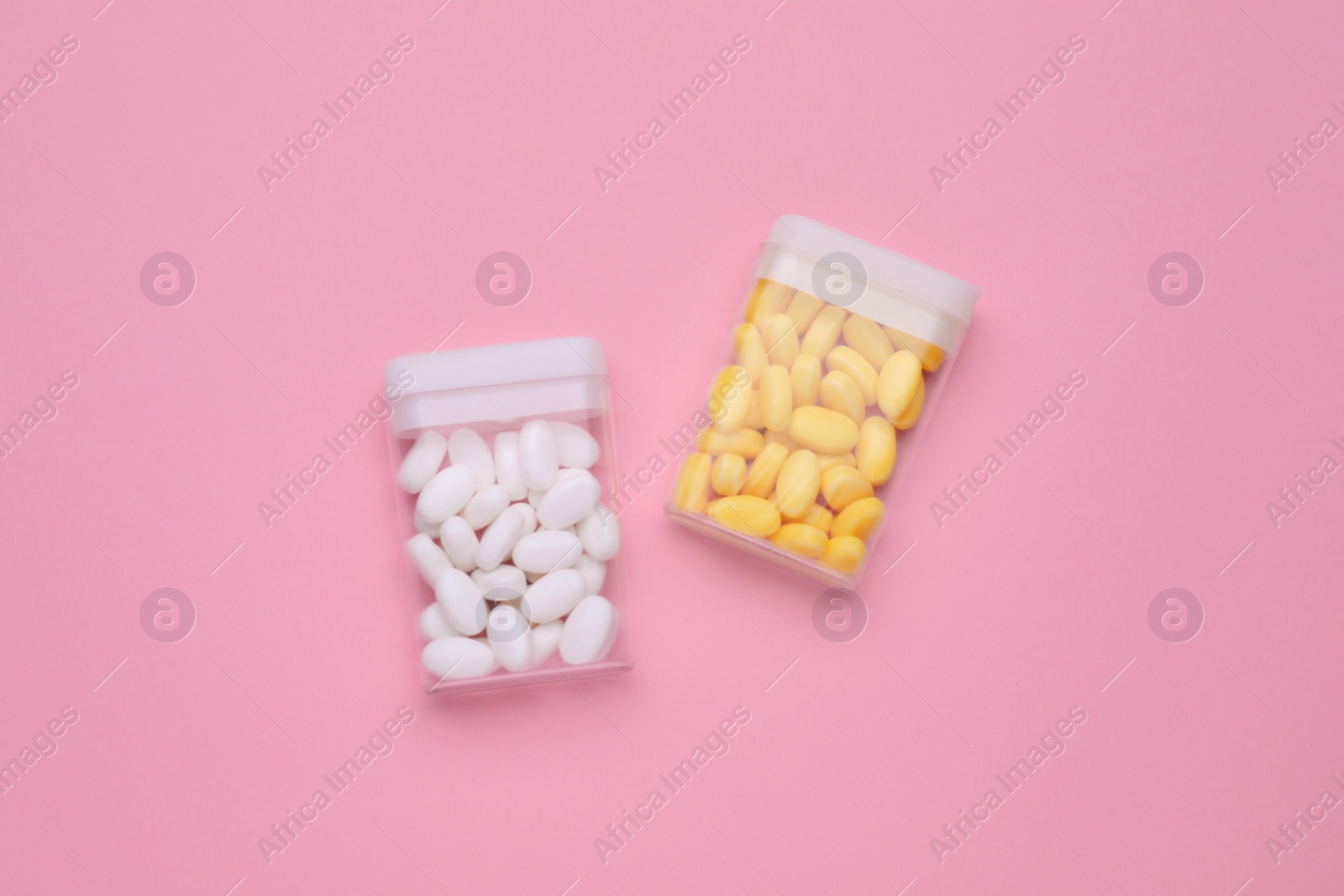 Photo of Containers with different dragee candies on pink background, flat lay