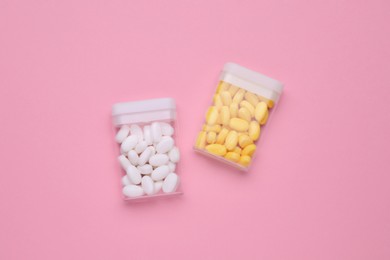 Photo of Containers with different dragee candies on pink background, flat lay