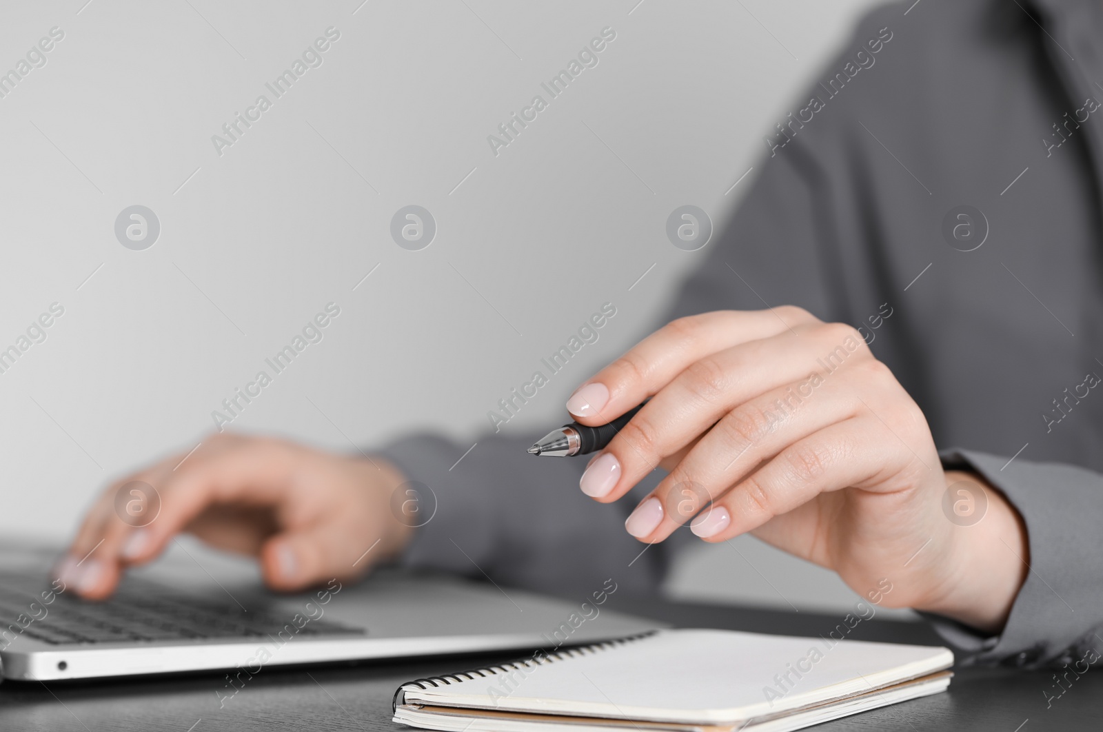 Photo of Woman with pen working on laptop, closeup. Electronic document management