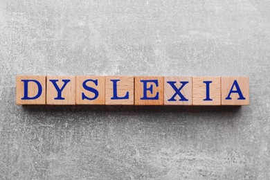 Photo of Wooden cubes with word Dyslexia on light grey stone table, flat lay