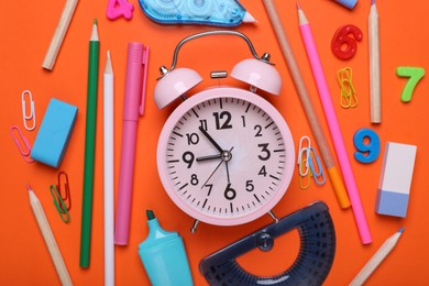 Flat lay composition with different school stationery and alarm clock on red background. Back to school