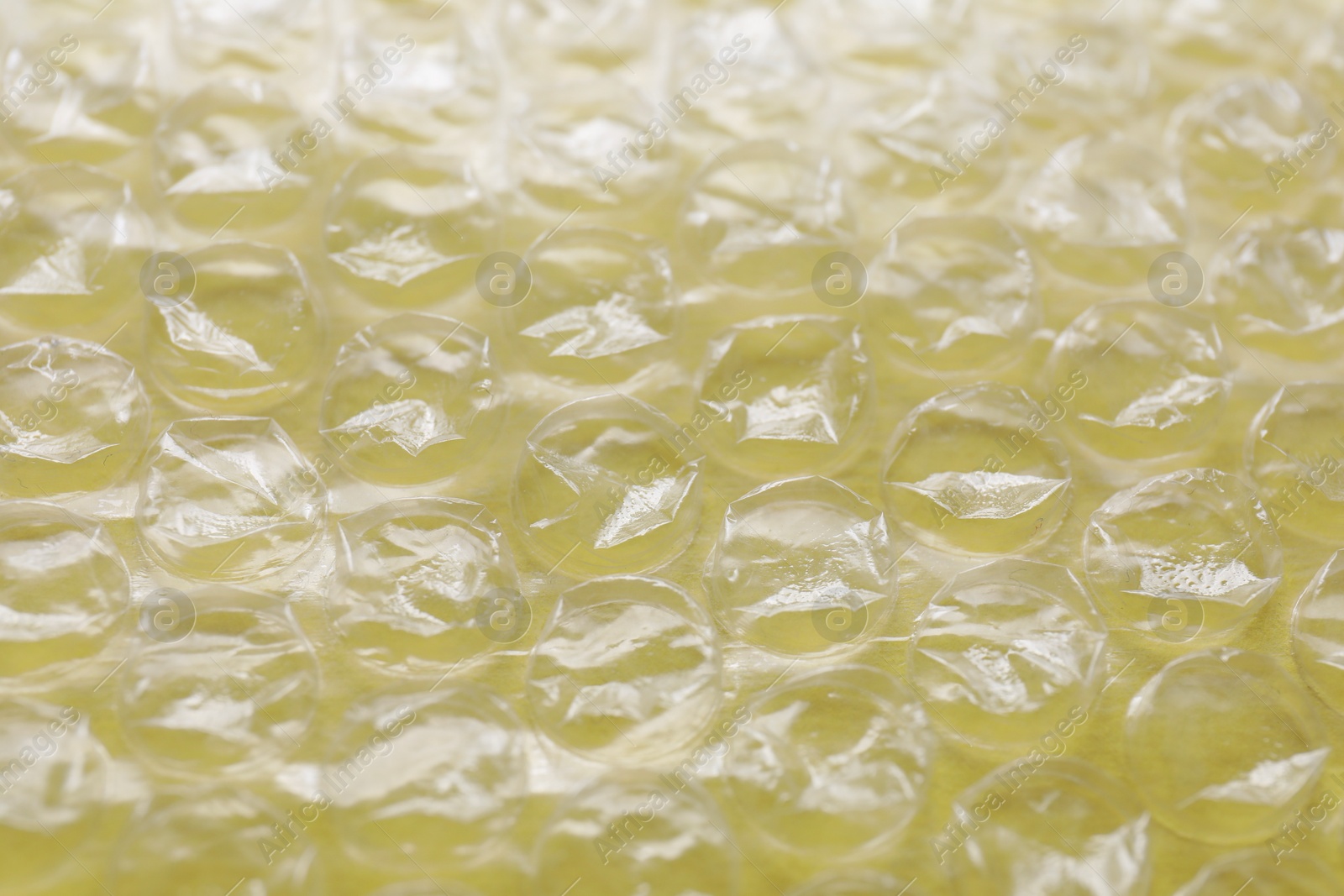 Photo of Transparent bubble wrap on yellow background, closeup