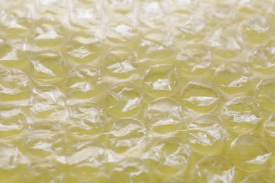 Photo of Transparent bubble wrap on yellow background, closeup