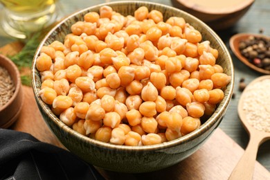 Photo of Bowl with delicious hummus on light blue wooden table, closeup