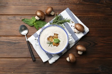 Delicious homemade mushroom soup served on wooden table, flat lay