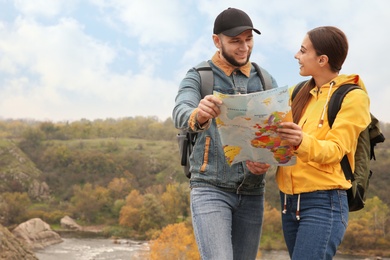 Photo of Couple of travelers with backpacks and map planning trip in mountains. Autumn vacation