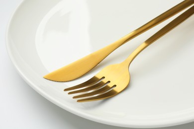 Clean plate, fork and knife on white background, closeup