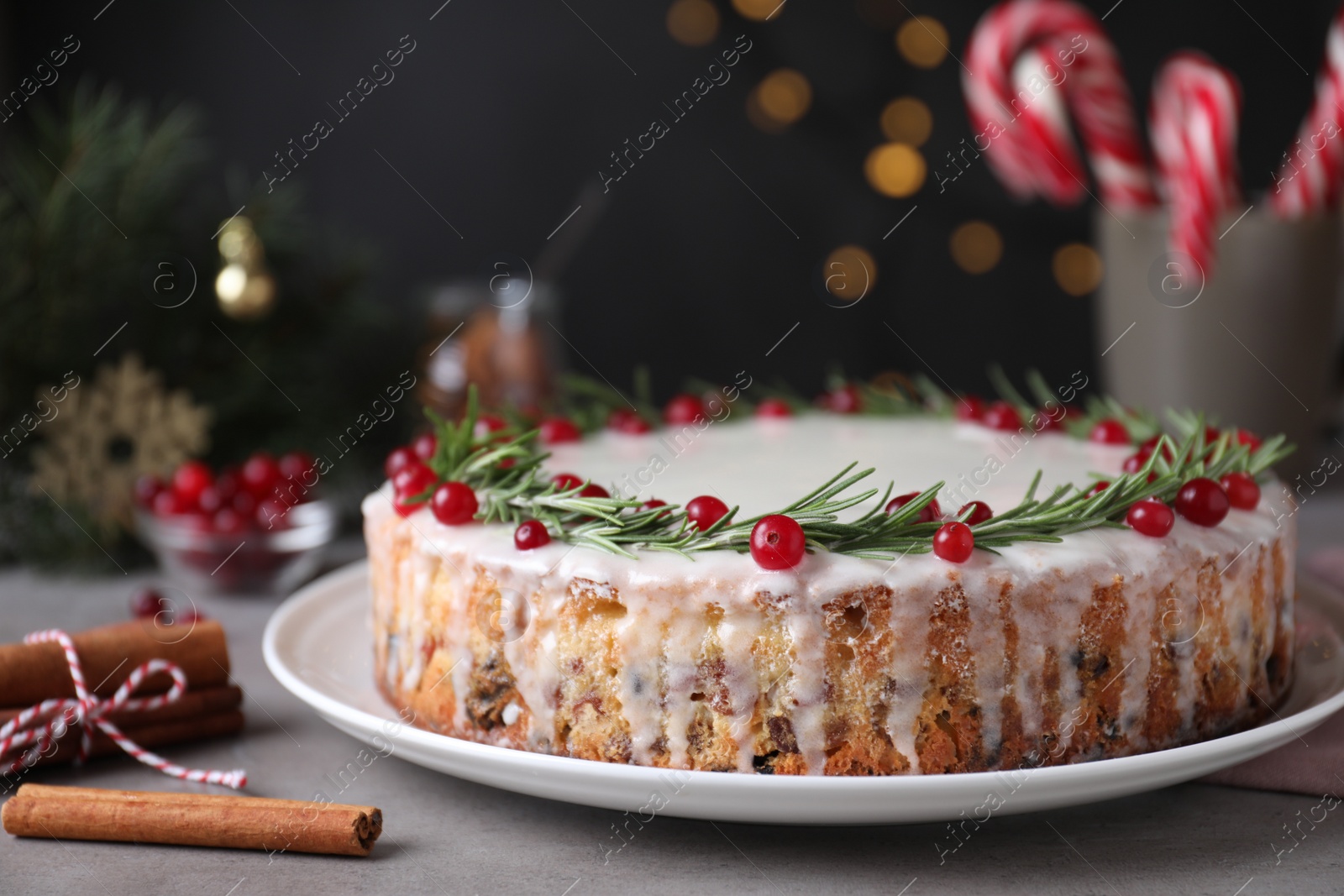 Photo of Traditional Christmas cake decorated with rosemary and cranberries on table, closeup