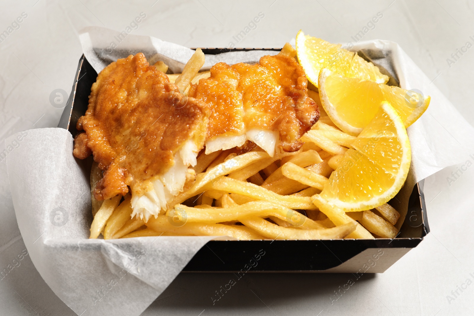 Photo of Container with British traditional fish and potato chips on table