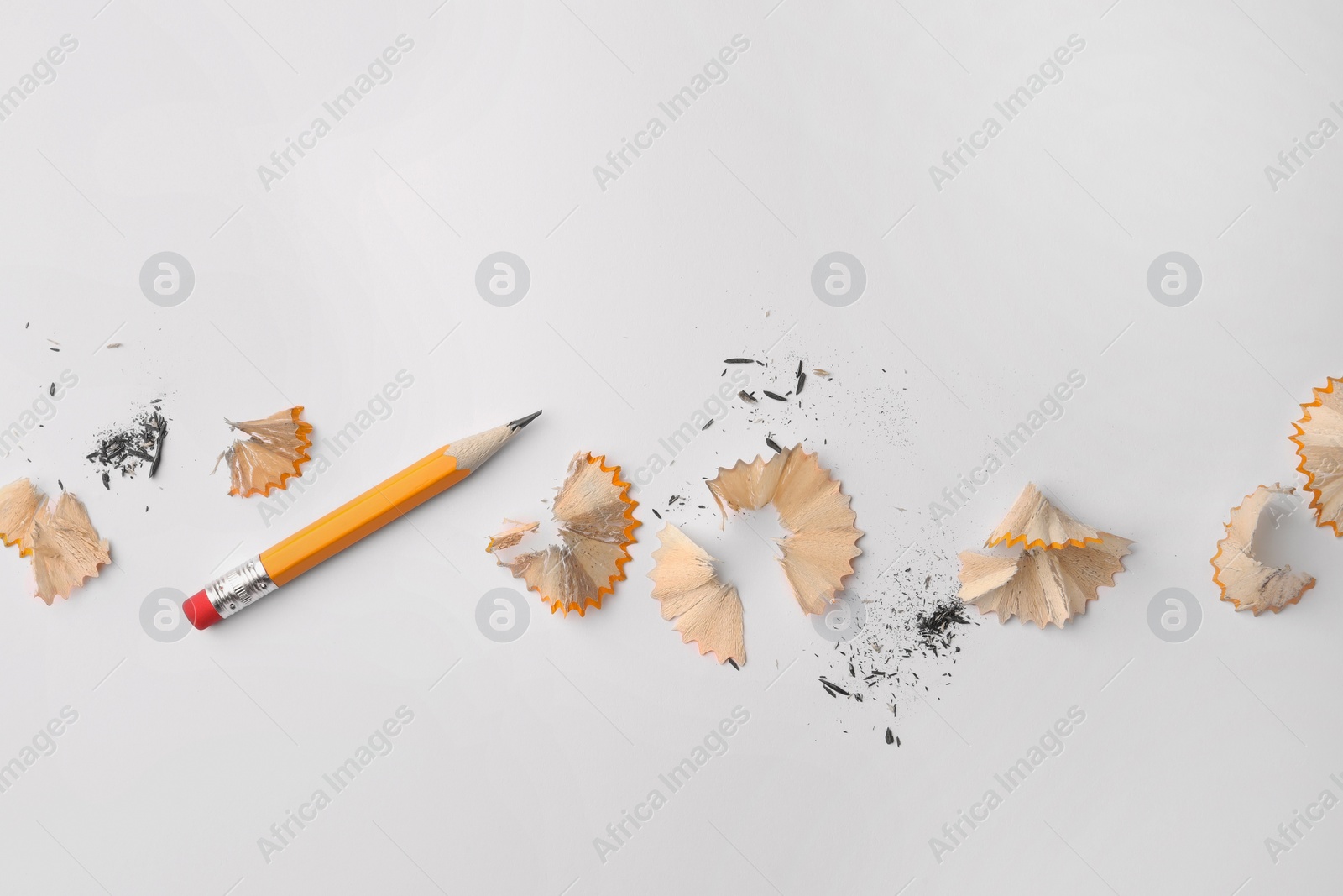 Photo of Graphite pencil and shavings on white background, flat lay