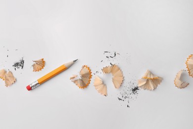 Photo of Graphite pencil and shavings on white background, flat lay