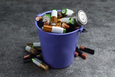 Used batteries and bucket on grey table