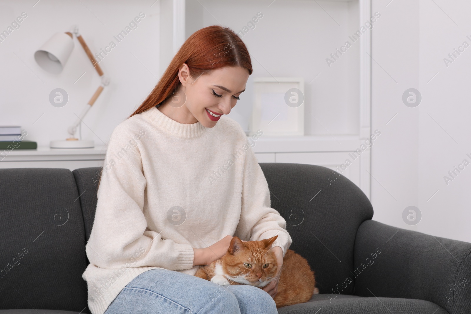 Photo of Happy woman with her cute cat on sofa at home