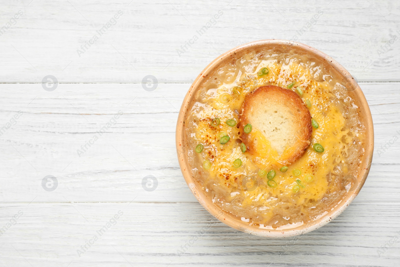 Photo of Tasty homemade french onion soup on white wooden table, top view. Space for text
