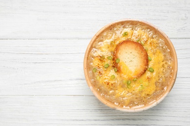 Tasty homemade french onion soup on white wooden table, top view. Space for text