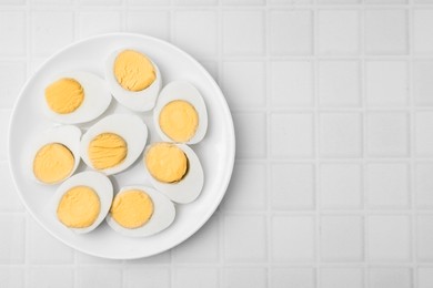Fresh hard boiled eggs on white tiled table, top view. Space for text