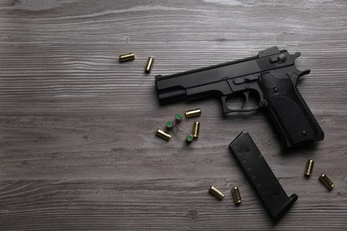 Photo of Pistol and bullets on wooden table, flat lay with space for text. Professional gun