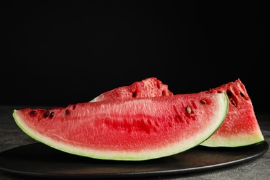 Photo of Yummy watermelon slices on grey table against black background