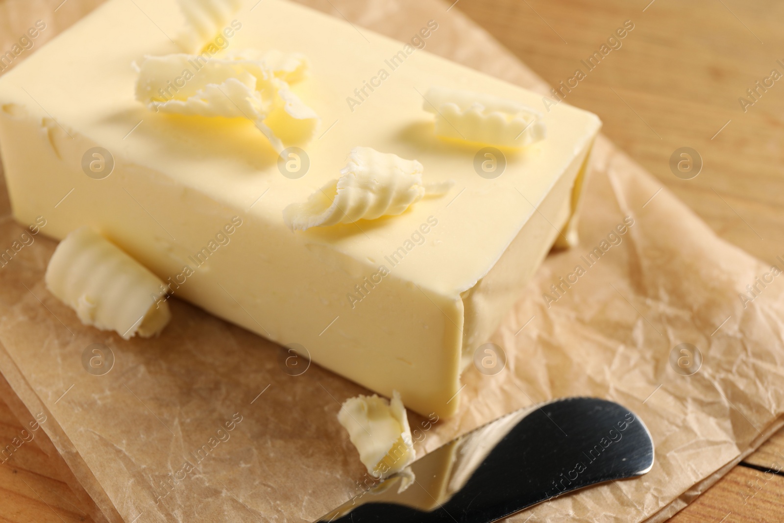 Photo of Tasty butter and knife on wooden table, closeup